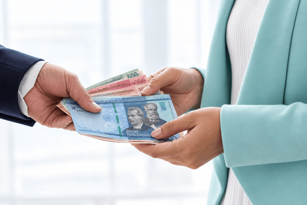 Intercambio de dinero entre dos manos, mostrando billetes dominicanos de diferentes denominaciones.