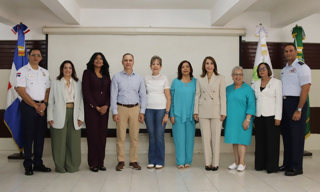 Grupo de personas posando juntas, en un ambiente formal, con banderas al fondo.